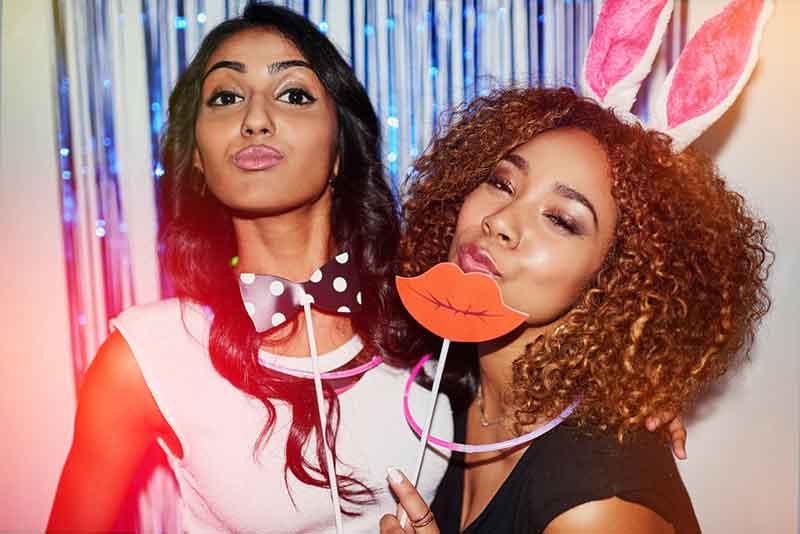 Friends with bunny ears and lip props at a photo booth