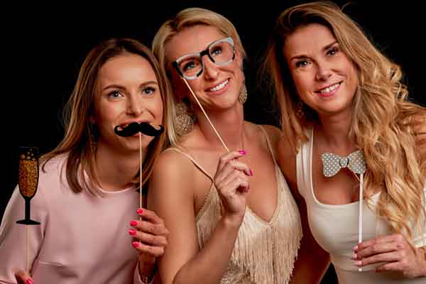 Three friends laughing with photo booth props