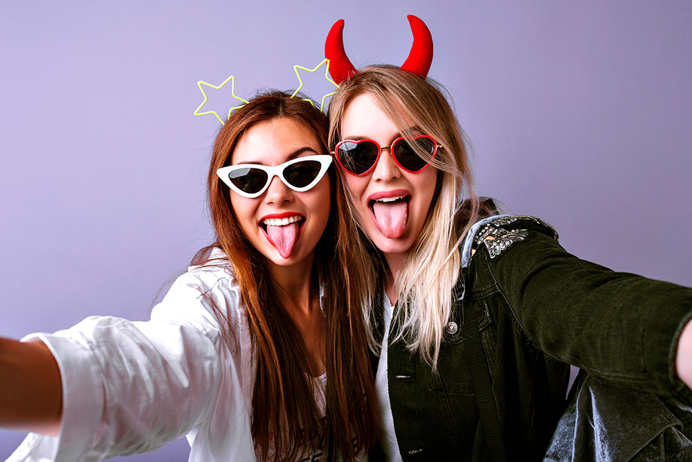 Young women taking a selfie with devil horn props