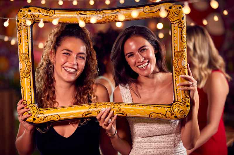 Friends holding a decorative gold frame at a photo booth