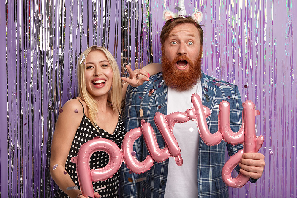 Couple celebrating with pink party balloons at a photo booth